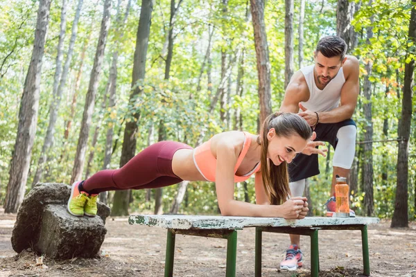 Hermosa mujer haciendo una tabla con el hombre mirando — Foto de Stock