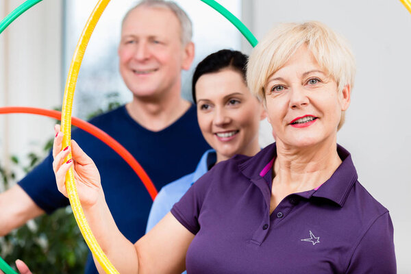 Старшая пара в физиотерапии делает упражнения с обручем хула
