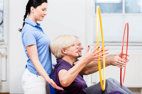 Senior couple in physiotherapy doing exercise with hula hoop — Stock Photo, Image