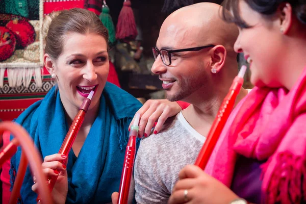 Women and man enjoying recreational shisha in hookah lounge — Stock Photo, Image