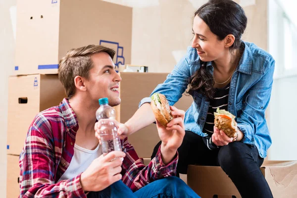 Casal jovem que parece cansado enquanto come um sanduíche durante a renovação — Fotografia de Stock