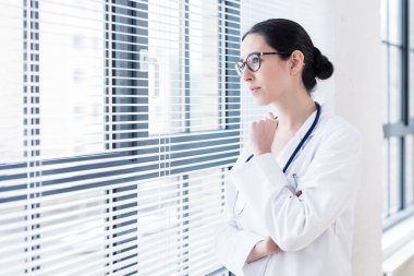 Pencereden bakarken hayal genç kadın doktor