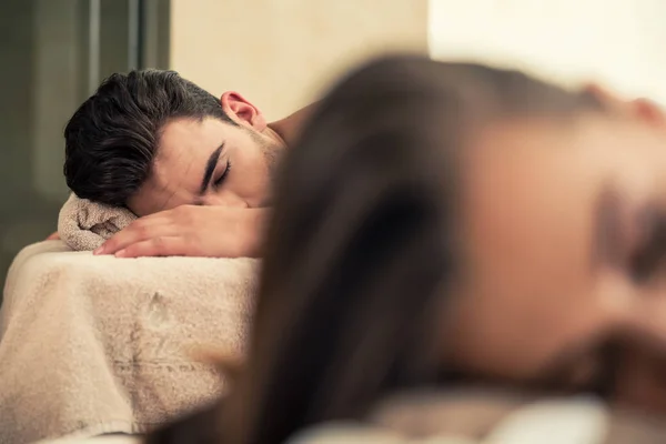 Homem relaxante com seu parceiro em camas de massagem no centro de bem-estar — Fotografia de Stock