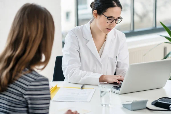 Médico de atención primaria escribiendo en el ordenador portátil observaciones útiles — Foto de Stock