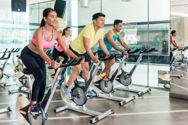 Ženy spalování kalorií během lekce indoor cyclingu ve fitness klubu — Stock fotografie