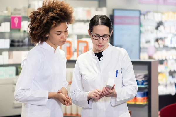 Two pharmacists analyzing the package of a new pharmaceutical drug — Stock Photo, Image