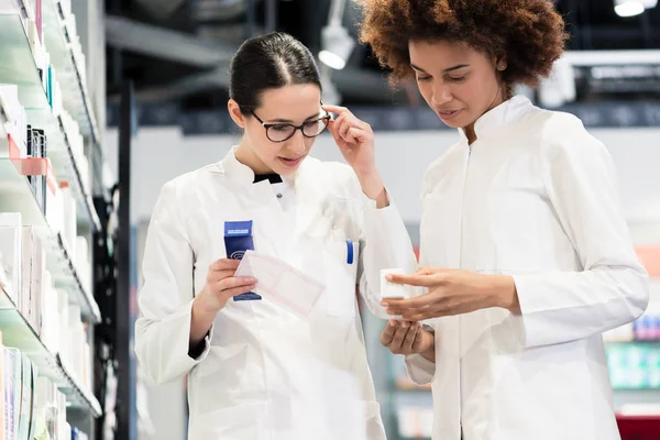 Zuverlässige Apotheker, die ein Rezept und zwei verschiedene Medikamente analysieren — Stockfoto