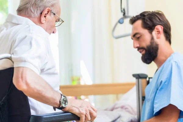 Ouderenzorg verpleegkundige helpen senior van bed naar rolstoel — Stockfoto