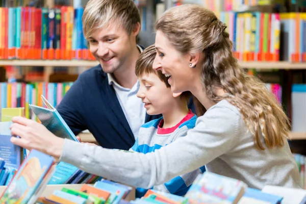 Família lendo um livro na biblioteca — Fotografia de Stock