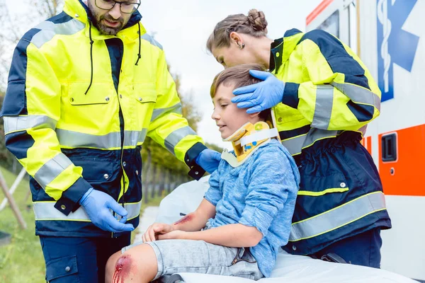 Médecins d'urgence prenant soin d'un garçon blessé — Photo