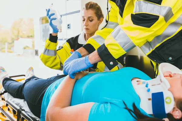 Médecins avec femme blessée donnant une perfusion — Photo