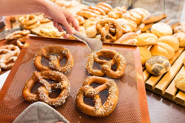 Venditrice in panetteria che vende pretzel e pane — Foto Stock