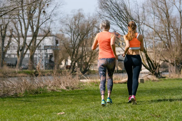 Mother and adult daughter running for sport along the river — Stock Photo, Image