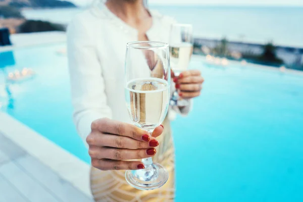 Woman handing glass of sparkling wine at pool and beach party — Stock Photo, Image