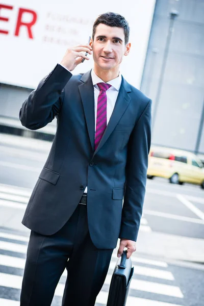 Man in suit talking on phone crossing street — Stock Photo, Image