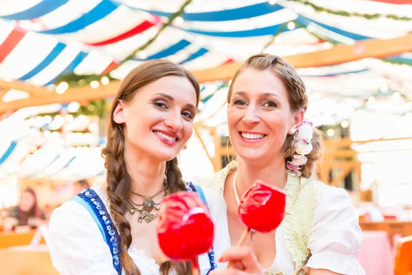 Friends in a beer tent holding candy apples — Stock Photo, Image