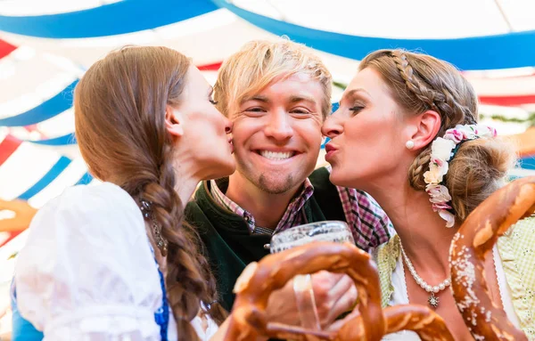 Two women kissing man at Bavarian beer tent