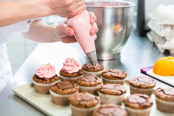 Mulheres em pastelaria como confeiteiro vidros muffins com cobertura — Fotografia de Stock