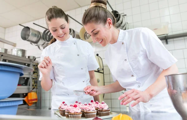 Dos mujeres panaderas en pastelería trabajando en magdalenas — Foto de Stock