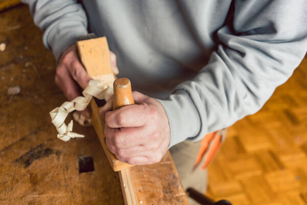 Hand of a senior carpenter with wood planer