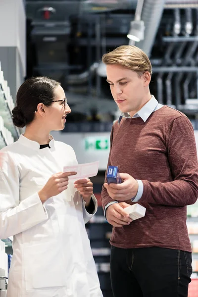 Joven sosteniendo dos medicamentos mientras mira varios productos — Foto de Stock