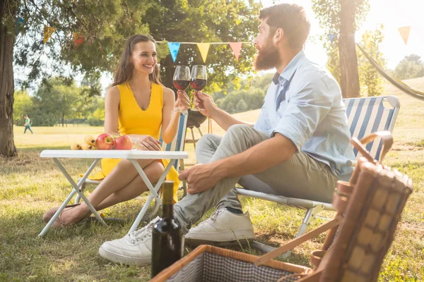 年轻和美丽的情侣在浪漫的野餐中坐在折叠椅上 在乡下的时候 在爱中举杯祝酒 — 图库照片