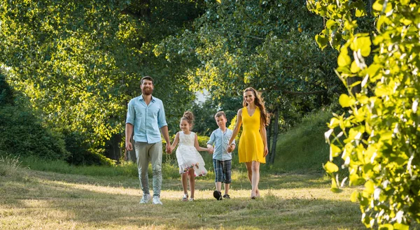 Glückliche Familie mit zwei Kindern Händchen haltend beim Freizeitspaziergang — Stockfoto