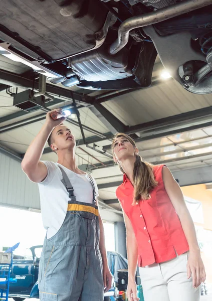 Zuverlässiger Automechaniker überprüft das Auto einer Frau in einer modernen Werkstatt — Stockfoto