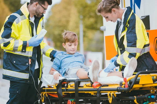 Médicos poniendo niño herido en camilla después de accidente — Foto de Stock