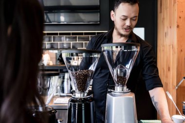 Genç barista kahve taze öğütülmüş kavrulmuş fasulye hazırlama 