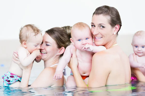 Las madres y sus hijos pequeños se divierten en la lección de natación del bebé — Foto de Stock