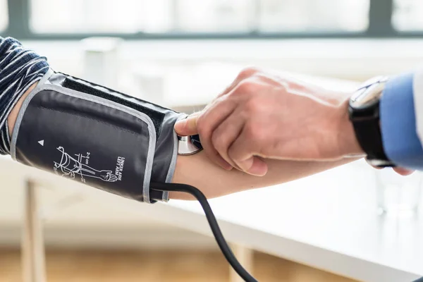 Mão de um médico que mede a pressão arterial de um paciente — Fotografia de Stock