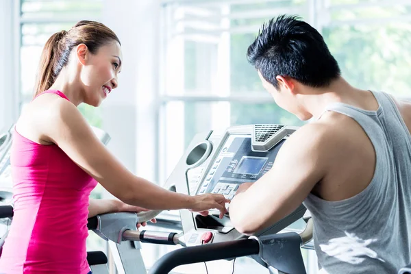 Coach supervising young Asian woman on treadmill — Stock Photo, Image