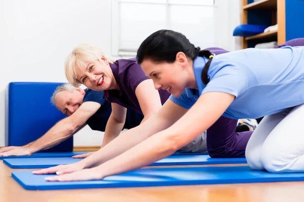 Fisio haciendo kinesioterapia con pacientes mayores — Foto de Stock