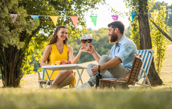Gelukkige paar roosteren met rode wijn, terwijl de viering van hun liefde — Stockfoto