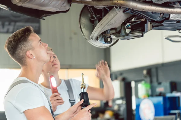 Wykwalifikowanych auto mechanik wymiana amortyzatorów samochodu w warsztacie — Zdjęcie stockowe