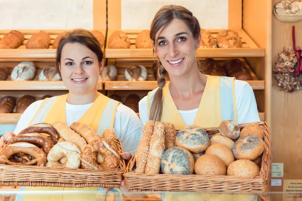 Two salesladies in bakery with basket of bread — Stock Photo, Image