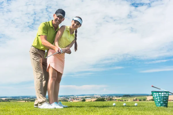 Young woman practicing the correct move during golf class with a skilled player — Stock Photo, Image