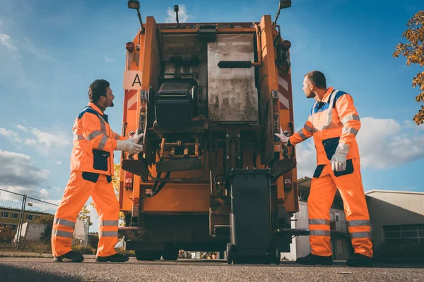 Zwei Mitarbeiter der Müllabfuhr laden Müll in Müllwagen — Stockfoto