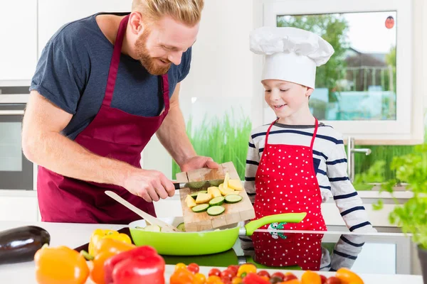 Father and son preparing food together in kitchen — Stock Photo, Image
