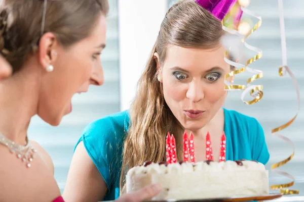 Young woman making a funny face while blowing out the candles — Stock Photo, Image