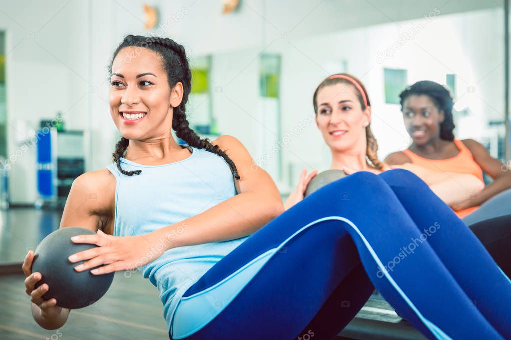 Beautiful woman exercising Russian twist with med ball for strong abs