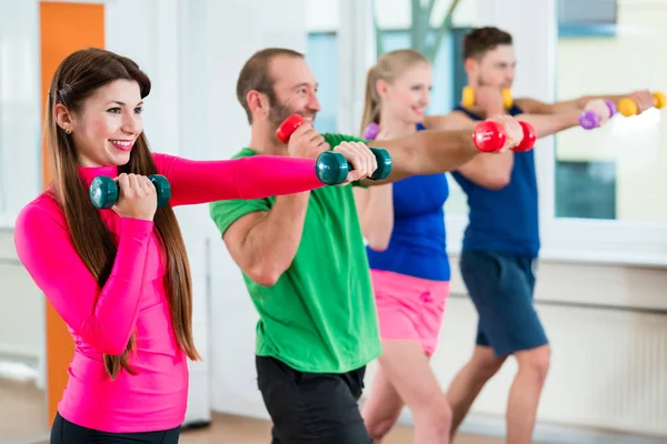 Grup dumbbells ile jimnastik yaparken spor salonunda sporcuların — Stok fotoğraf