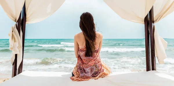 Mujer sentada en la cama de playa mirando al mar —  Fotos de Stock