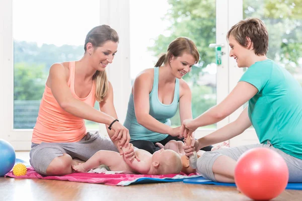 Mujeres jóvenes practicando cómo envolver a los niños en la madre-hijo menos — Foto de Stock