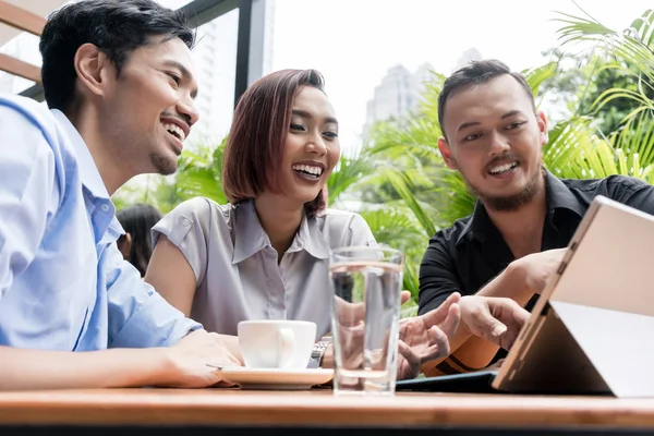Tres jóvenes amigos asiáticos sonriendo mientras usan juntos una tableta —  Fotos de Stock