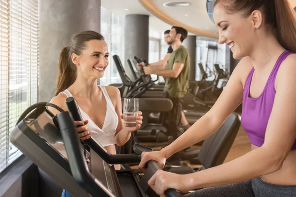 Young woman helping her friend to set the parameters of treadmill — Stock Photo, Image