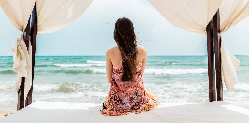 Woman sitting in beach bed looking at the sea