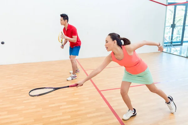 Mulher chinesa competitiva segurando a raquete durante um jogo de squash — Fotografia de Stock