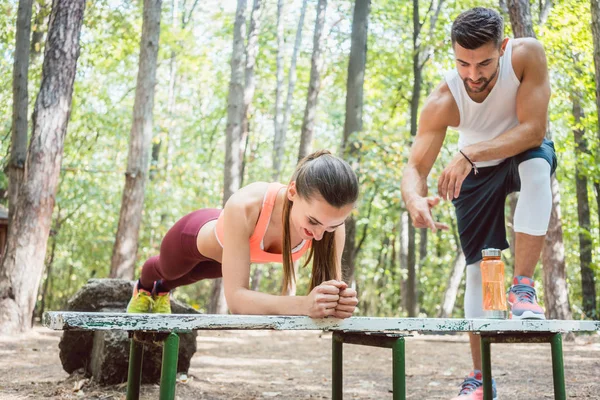 Hermosa mujer haciendo una tabla con el hombre mirando —  Fotos de Stock